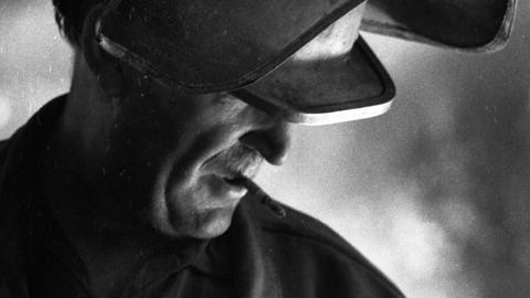 Historisches Schwarzweißfoto eines Zigarette rauchenden Arbeiters in Schutzkleidung am Hochofen. 1970 