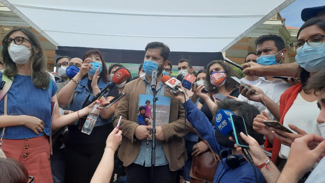 Ein junger Mann mit Vollbart und Mundschutz wird umringt von Journalisten, die ihm ihre Mikrofone entgegenstrecken.