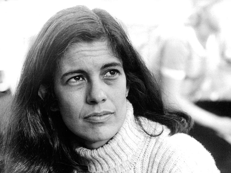 Die Archivaufnahme der 1933 geborenen Intellektuellen Susan Sontag entstand in Stockholm am 6. august 1970. Sie zeigt die Frau mit weißem Rollkragenpulli und langen dunklen Haaren. Sie schaut links an der Kamera vorbei in die Ferne.  