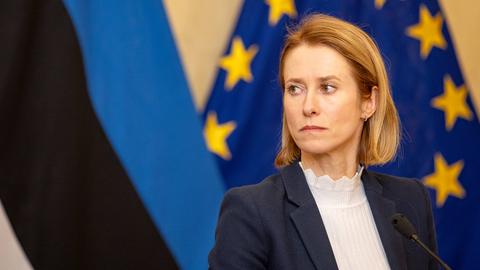 Kaja Kallas steht auf der Bühne und blickt ernst zur Seite. Hinter ihr sind die estnische und die EU-Flagge zu sehen.