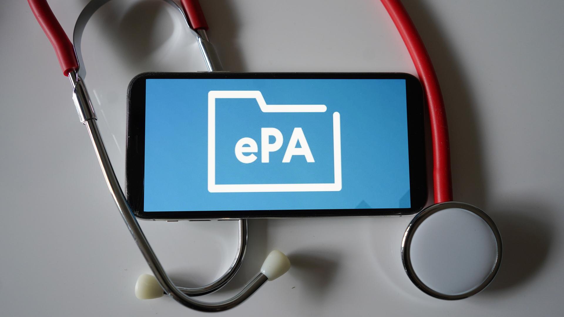 Ein Smartphone, auf dem das Symbol der elektronischen Patientenakte (ePA) zu sehen ist, liegt auf einem Stethoskop.
