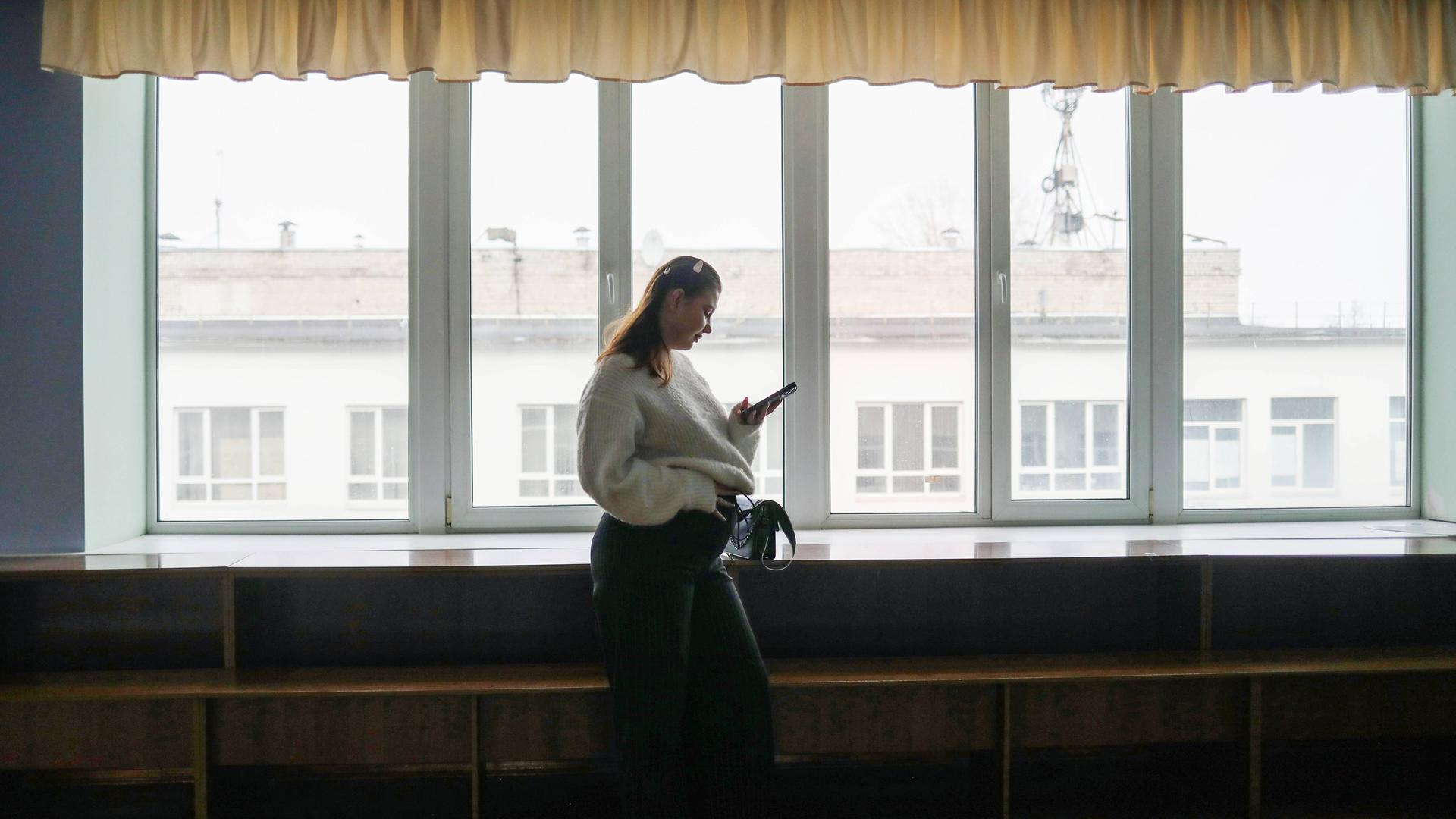 Die schwangere Studentin Alisa Khokhlova an der Staatlichen Dobrolyubov-Universität in Nischni Nowgorod, Russland. Sie steht alleine an einem Fenster und hält ihren Bauch. Die schwangere Studentin Alisa Khokhlova an der Staatlichen Dobrolyubov-Universität in Nischni Nowgorod, Russland. Sie steht alleine an einem Fenster und hält ihren Bauch.