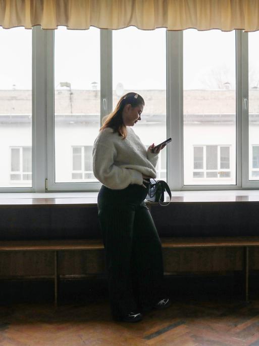 Die schwangere Studentin Alisa Khokhlova an der Staatlichen Dobrolyubov-Universität in Nischni Nowgorod, Russland. Sie steht alleine an einem Fenster und hält ihren Bauch.
