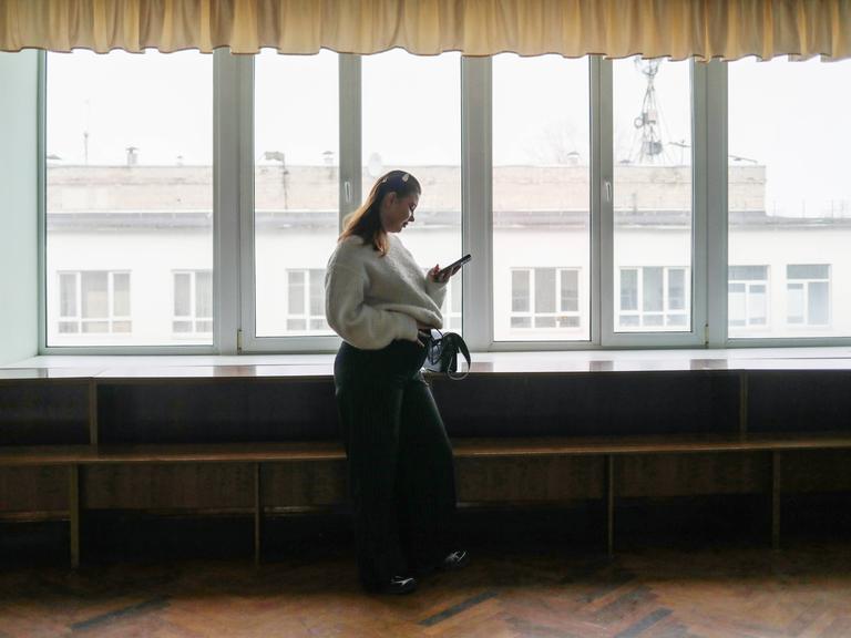 Die schwangere Studentin Alisa Khokhlova an der Staatlichen Dobrolyubov-Universität in Nischni Nowgorod, Russland. Sie steht alleine an einem Fenster und hält ihren Bauch.