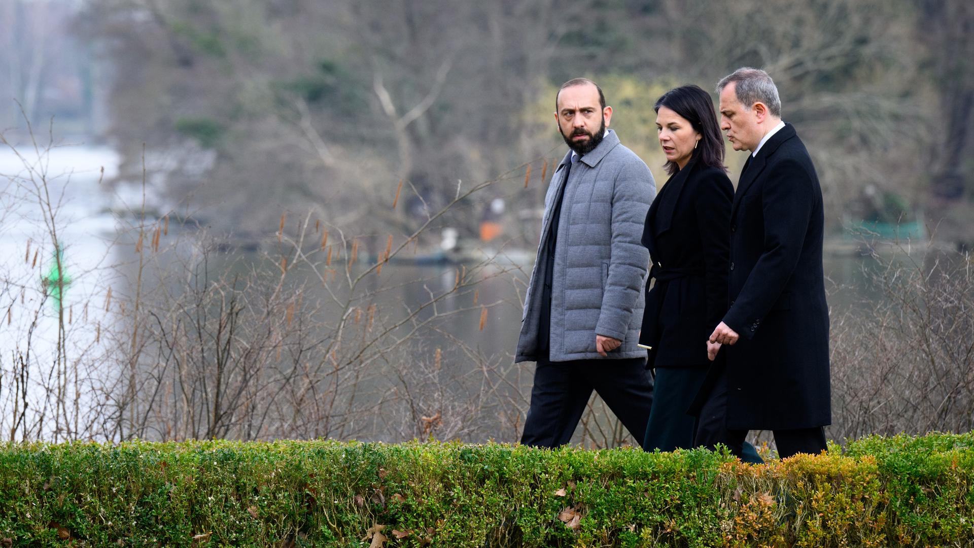 Armeniens Außenminister Ararat Mirzoyan und sein aserbaidschanischer Amtskollege Jeyhun Bayramov laufen mit Außenministerin Annalena Baerbock durch einen Park.

