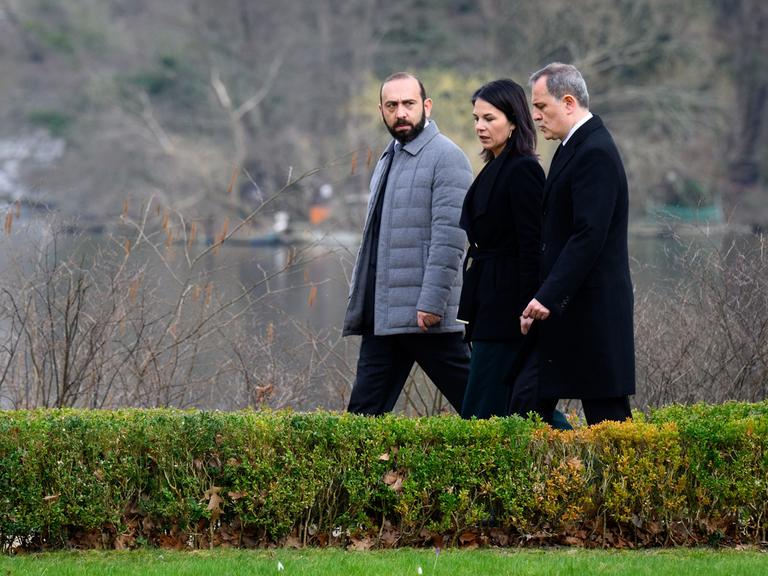 Armeniens Außenminister Ararat Mirzoyan und sein aserbaidschanischer Amtskollege Jeyhun Bayramov laufen mit Außenministerin Annalena Baerbock durch einen Park.
