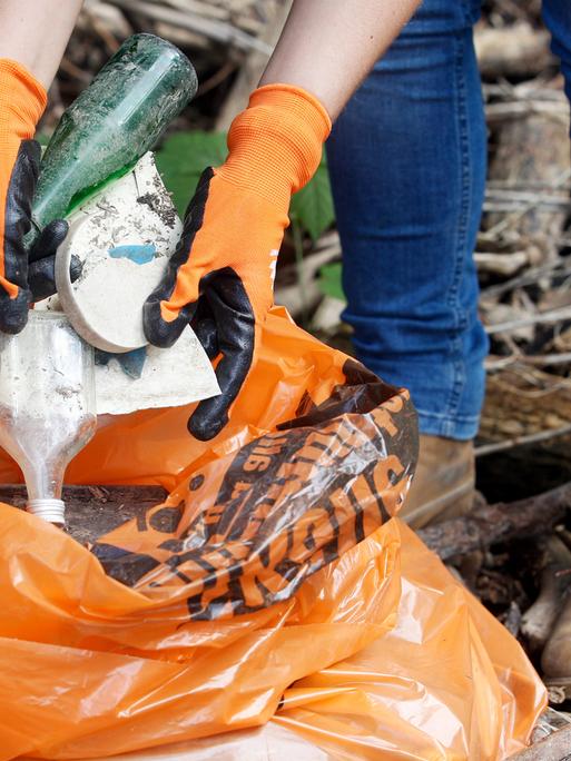 Eine freiwillige Helferin wirft den am Kölner Rheinufer gefundenen Müll in einen Müllsack