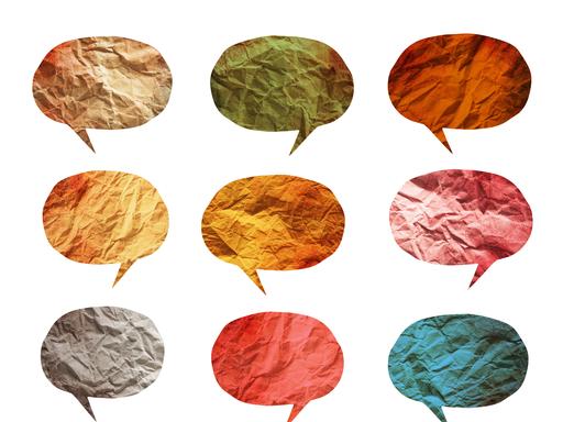 Eine Grafik zum Thema Mehrsprachigkeit: Sprechblasen aus Papier und in verschiedenen Farben sind auf einem weißen Hintergrund.