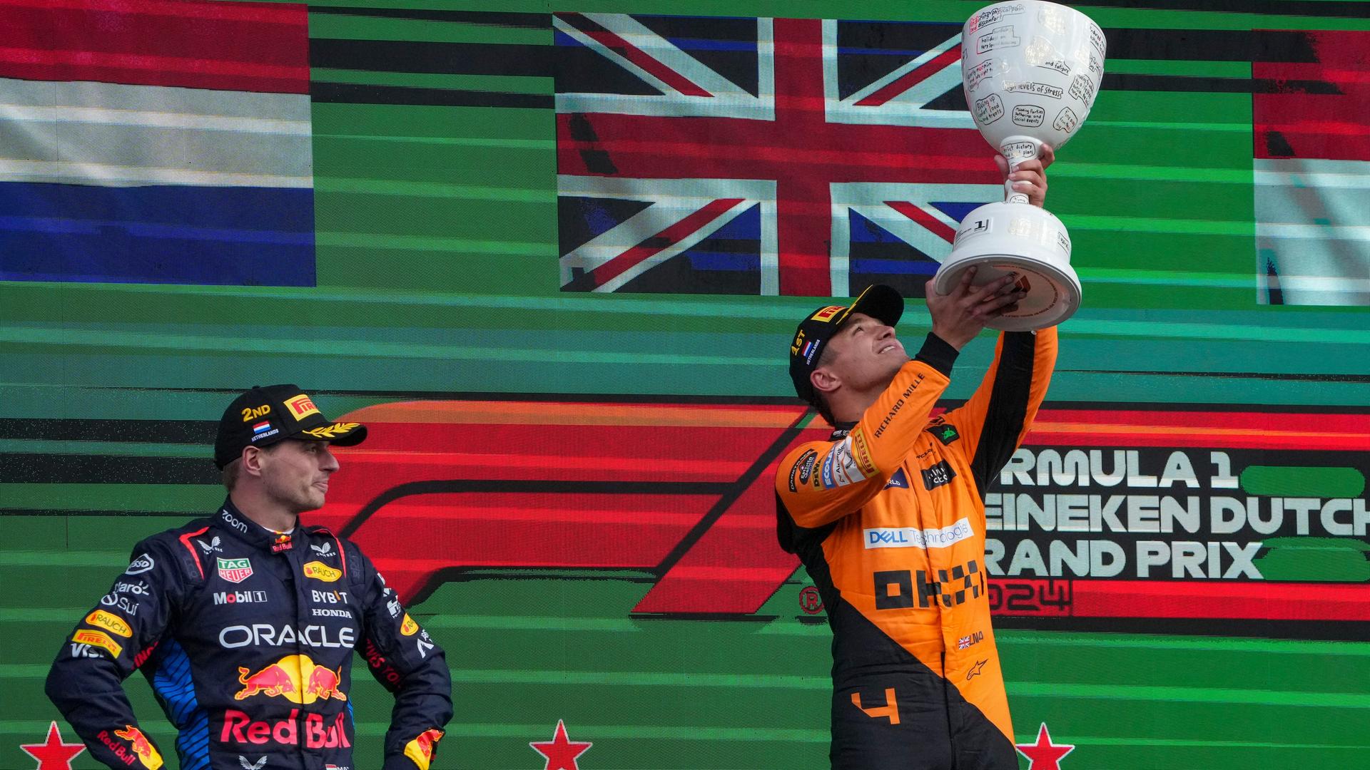 Sieger Lando Norris hält den Pokal in die Luft; Max Verstappen, der Zweiter wurde, steht links neben ihm. Sieger Lando Norris hält den Pokal in die Luft; Max Verstappen, der Zweiter wurde, steht links neben ihm.