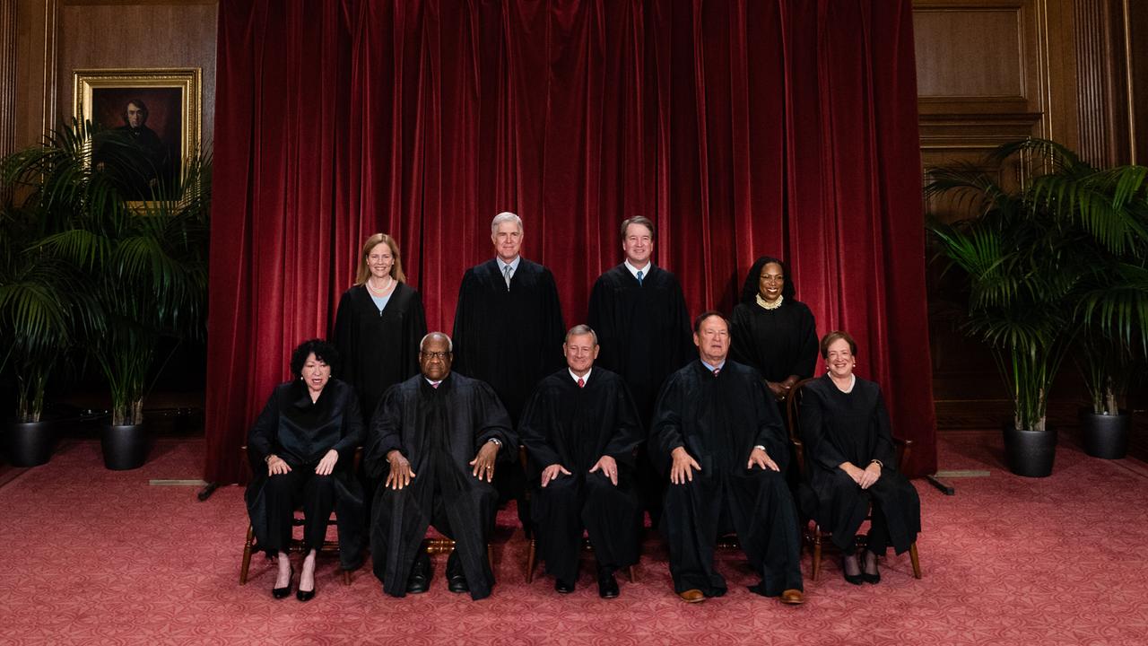 Die aktuellen Richterinnen und Richter des US Supreme Court sind für einen Fototermin teilweise sitzend, teilweise stehend vor einem schweren roten Vorhang aufgereiht.