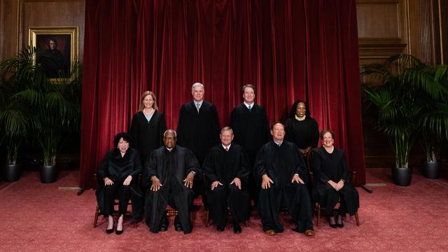 Die aktuellen Richterinnen und Richter des US Supreme Court sind für einen Fototermin teilweise sitzend, teilweise stehend vor einem schweren roten Vorhang aufgereiht.