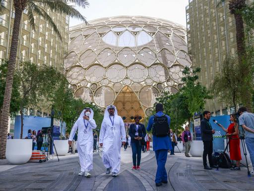 In der Expo City von Dubai findet die Klimakonferenz COP28 statt. Man sieht Teilnehmende und Journalisten auf der Plaza.