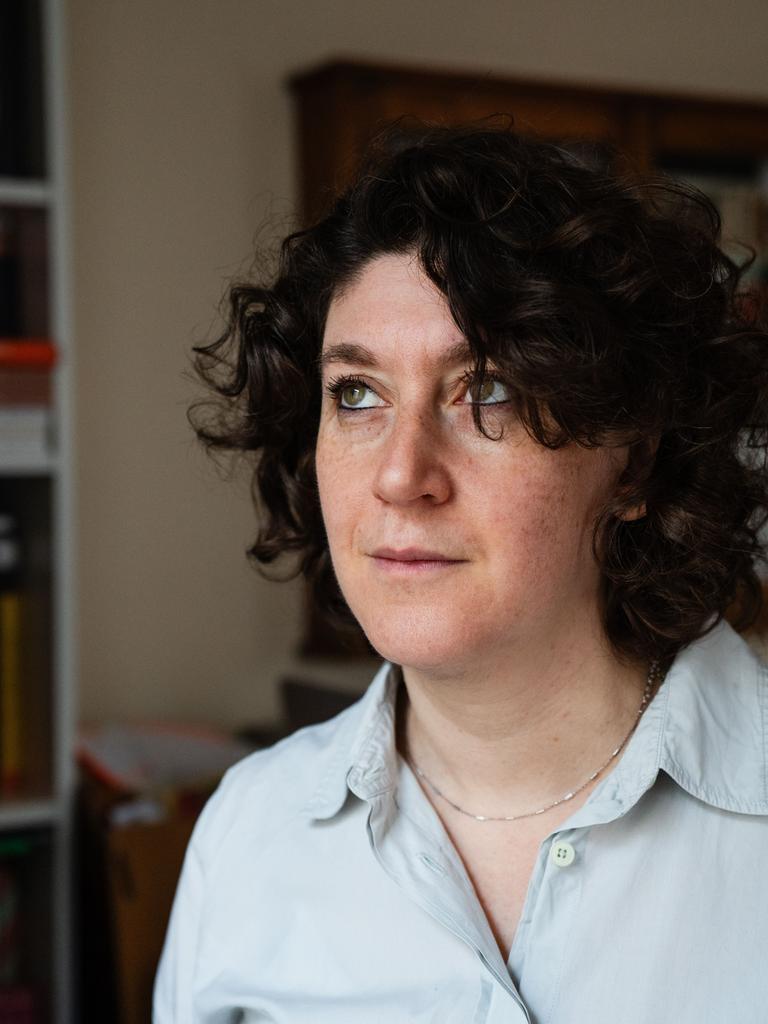 Eine Frau mit dunklen lockigen Haaren trägt ein weißes Hemd. Sie steht in einem Raum und blickt nach oben. Es ist die Autorin Lena Gorelik.
