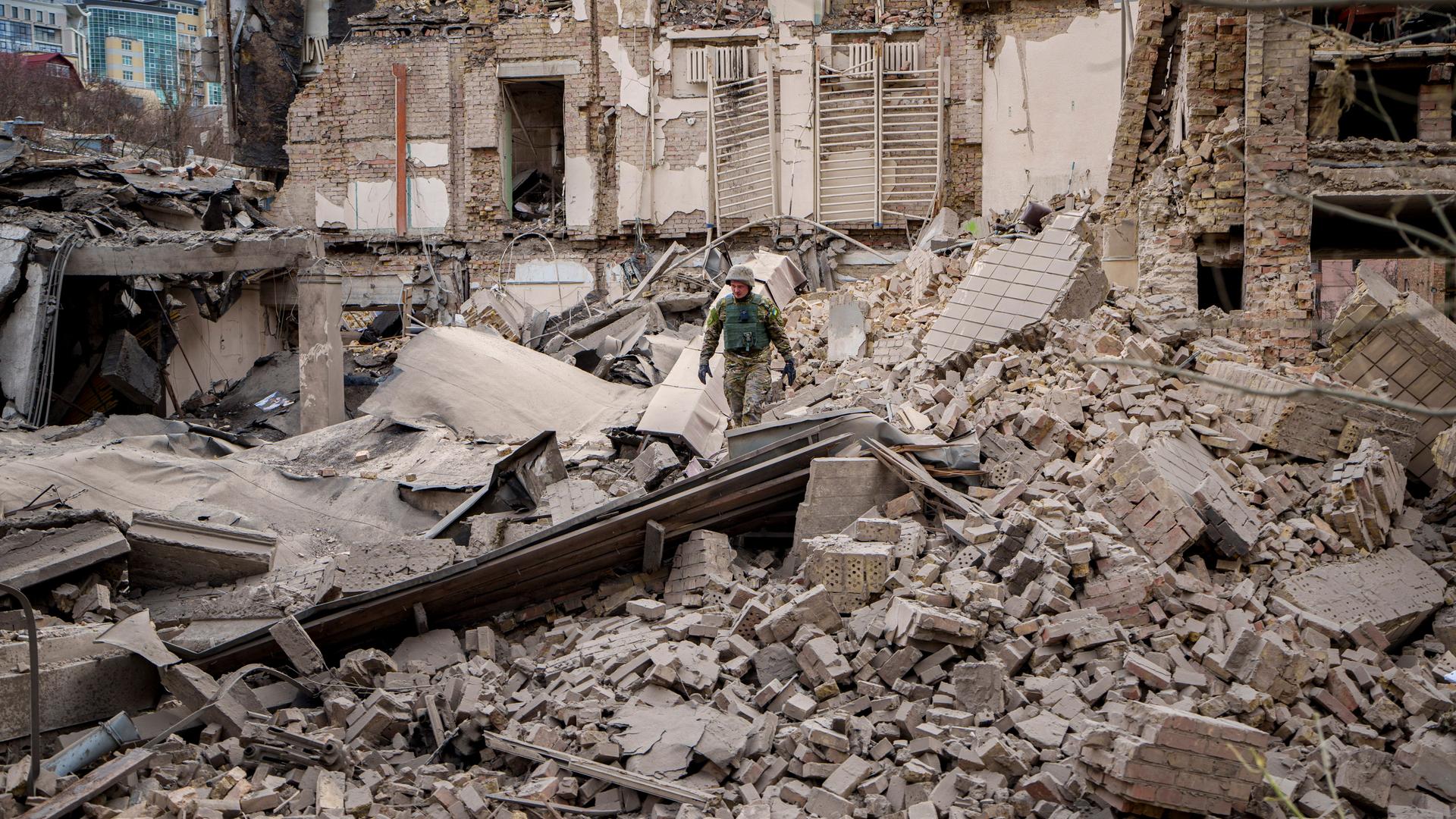 Ein ukrainischer Feuerwehrmann schaut sich in den Trümmern eines völlig zerstörten Hauses um.