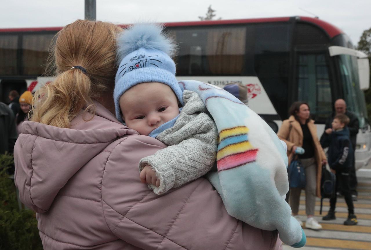 Ein Kleinkind liegt auf dem Arm seiner Mutter, die aus der ukrainischen Stadt Cherson flieht.