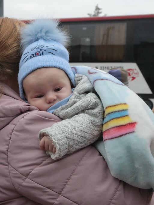 Ein Kleinkind liegt auf dem Arm seiner Mutter, die aus der ukrainischen Stadt Cherson flieht.