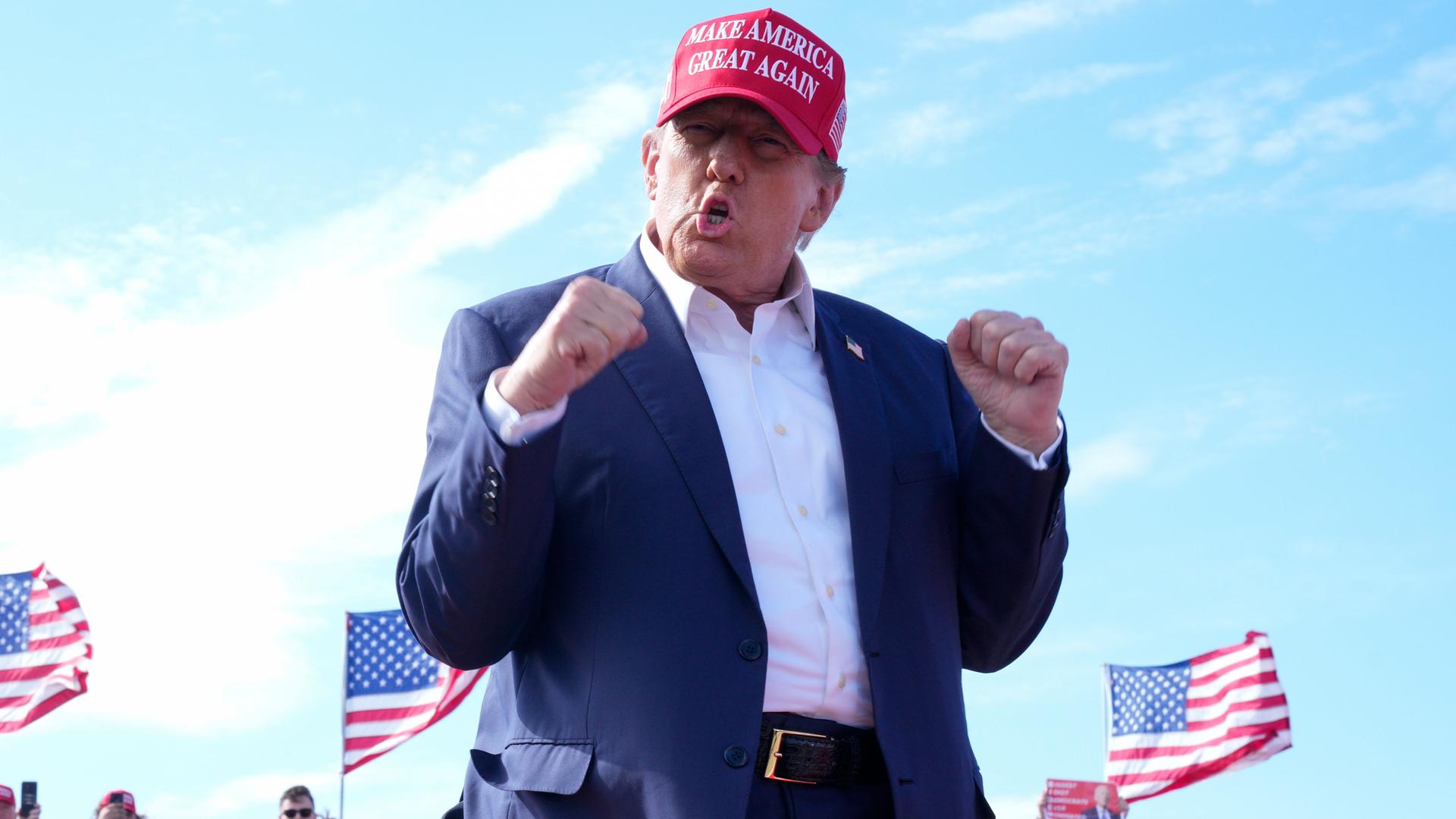 Donald Trump, ehemaliger US-Präsident und republikanischer Bewerber um die Präsidentschaftskandidatur, gestikuliert bei einer Wahlkampfveranstaltung in Vandalia, Ohio. Er trägt Hemd, Jacket und eine rote Mütze mit der Aufschrift "Make America Great Again".