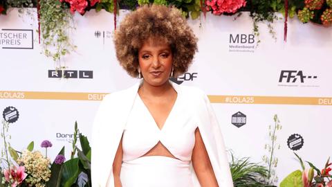 Benita Sarah Bailey bei der 75. Verleihung Deutscher Filmpreis. Sie trägt ein weißes Kleid und schaut in die Kamera.