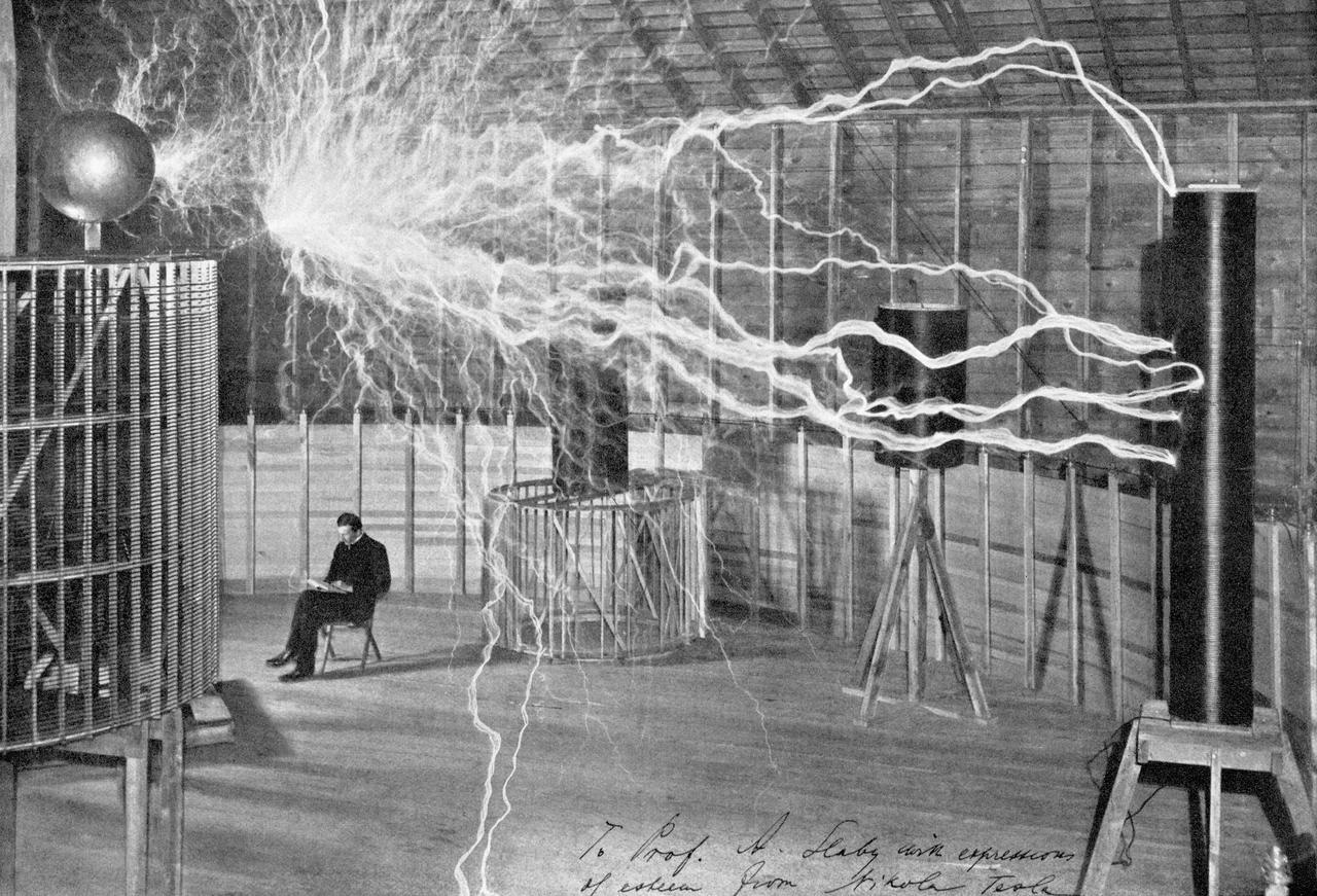 Tesla in seinem Labor in Colorado Springs im Dezember 1899. Die Aufnahme stellt eine Mehrfachbelichtung dar: Während der Blitzentladungen befand sich Tesla nicht im Raum.