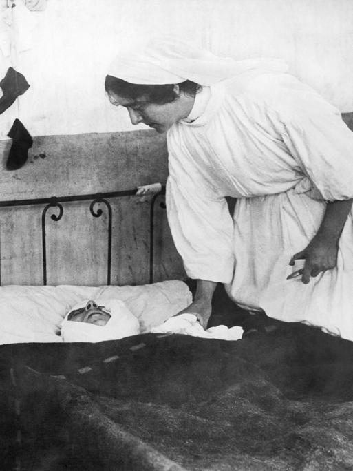 Historisches Schwarz-Weiß-Foto. Frankreich am 21. November 1914. Eine Krankenschwester kümmert sich um einen schwer verwundeten Soldaten, der in einem Krankenbett liegt.