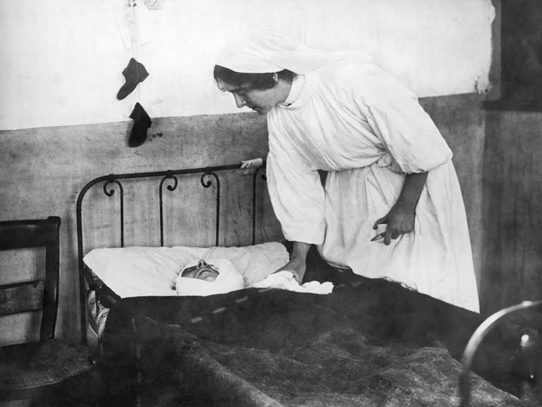 Historisches Schwarz-Weiß-Foto. Frankreich am 21. November 1914. Eine Krankenschwester kümmert sich um einen schwer verwundeten Soldaten, der in einem Krankenbett liegt.