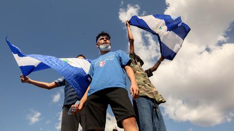 Junge Männer schwenken bei einem Protest in Managua Nationalflaggen. Sie fodern die Freilassung Hunderter seit 2018 inhaftierter Demonstranten.