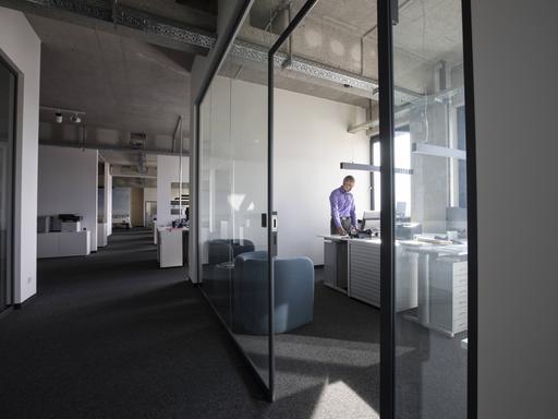 Ein Geschäftsmann allein in einem Büro mit Glastüren auf einer Büroetage