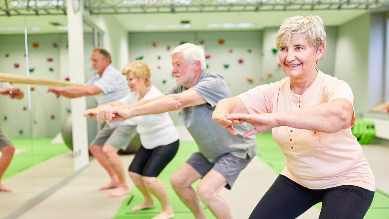 Senioren machen Kniebeugen für Kraft und Motorik.