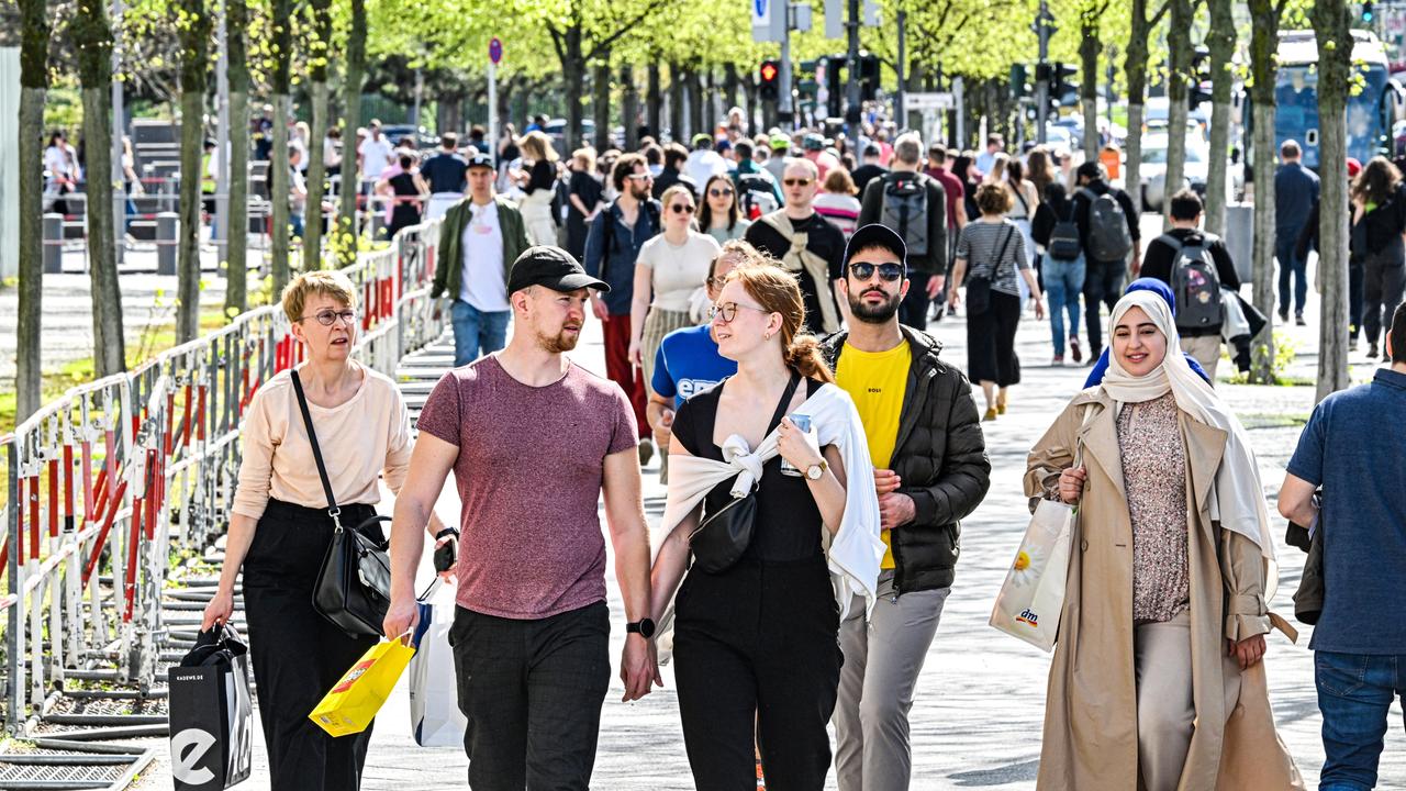 Frühlingswetter in Berlin: Menschen flanieren im April 2024 unter Bäumen