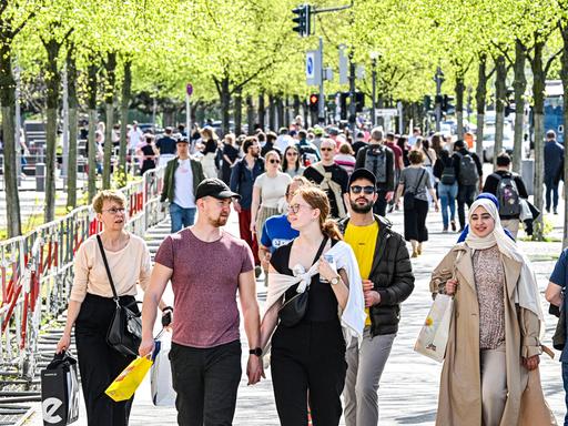 Frühlingswetter in Berlin: Menschen flanieren im April 2024 unter Bäumen Frühlingswetter in Berlin: Menschen flanieren im April 2024 unter Bäumen