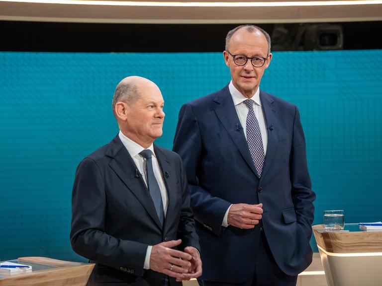 Bundeskanzler Olaf Scholz steht neben CDU-Kanzlerkandidat Friedrich Merz, vor dem TV-Duell von ARD und ZDF im Fernsehstudio.