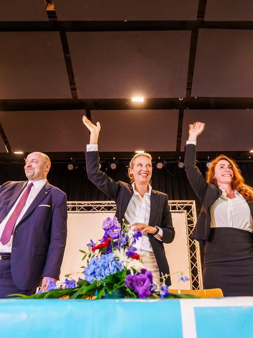 Robert Lambrou (l-r, AfD), AfD-Landesvorsitzender/Spitzenkandidat zur Landtagswahl, Alice Weidel (AfD), Bundesparteivorsitzende, und Mariana Harder-Kühnel (AfD), eine von drei stellvertretenden Bundessprechern ihrer Partei, stehen winkend und lachend auf dem Podium zusammen. 