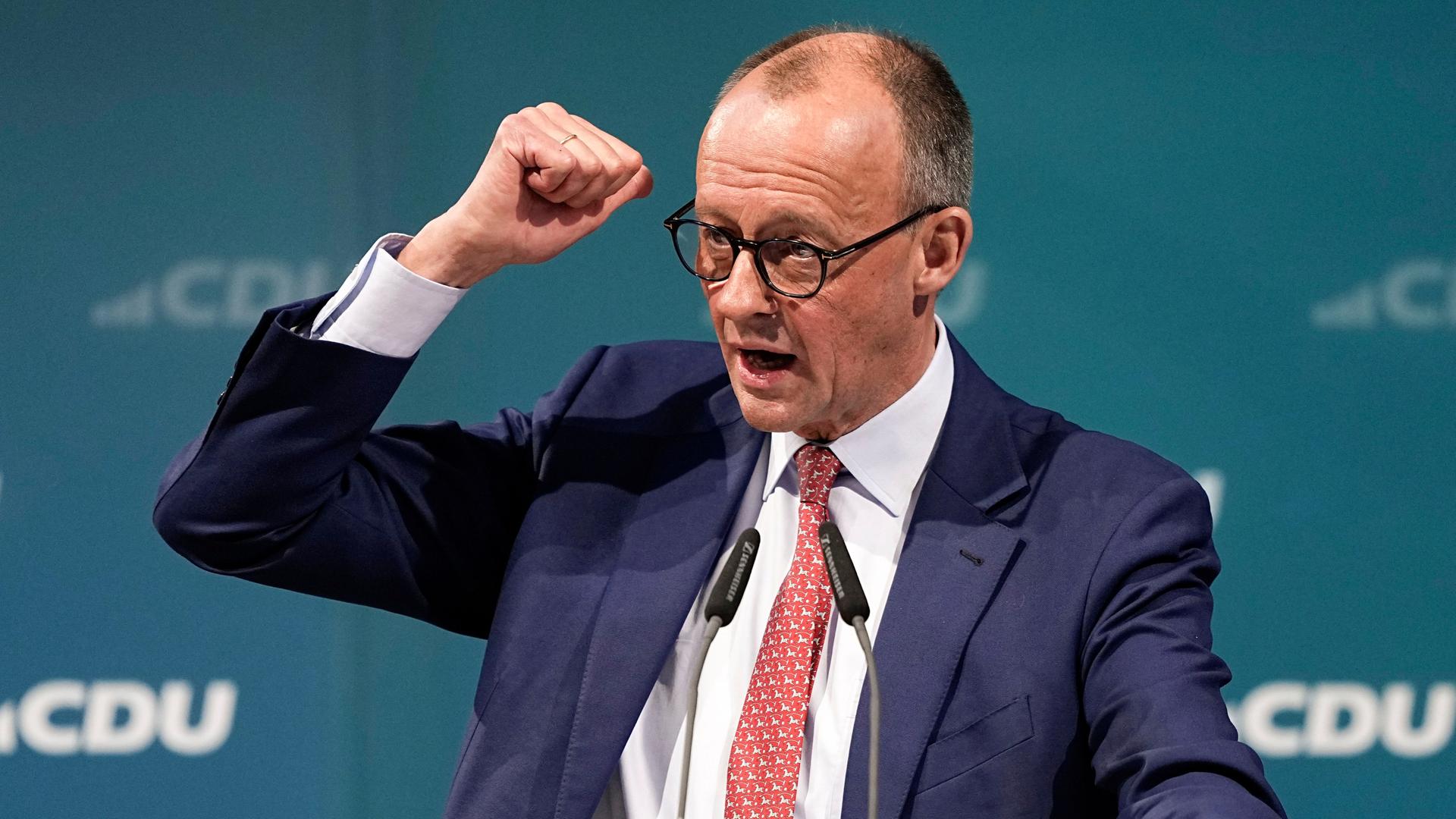 Friedrich Merz steht vor einer Wand mit dem CDU-Logo und spricht. Er gestikuliert mit der geballten rechten Hand.