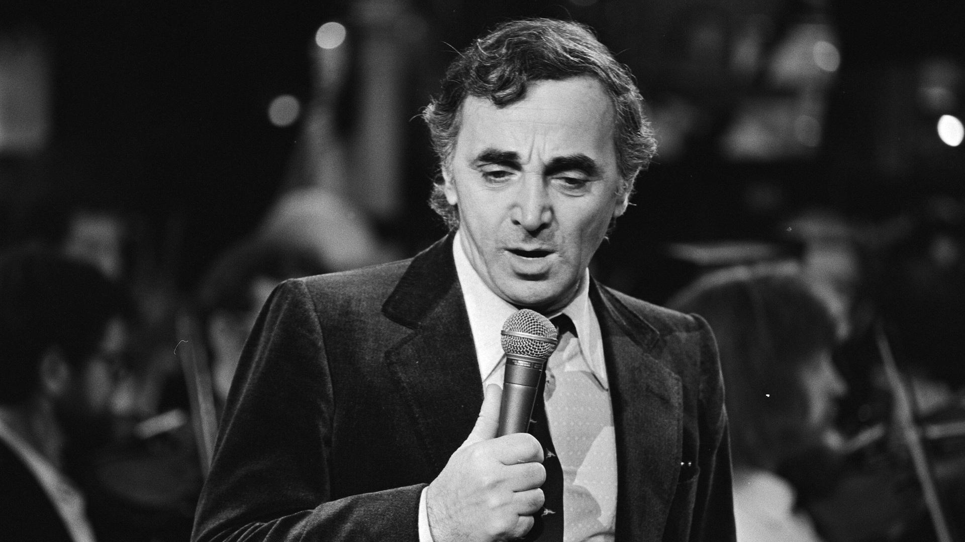 Der Sänger Charles Aznavourmit einem Mikrophon in der Hand. 
