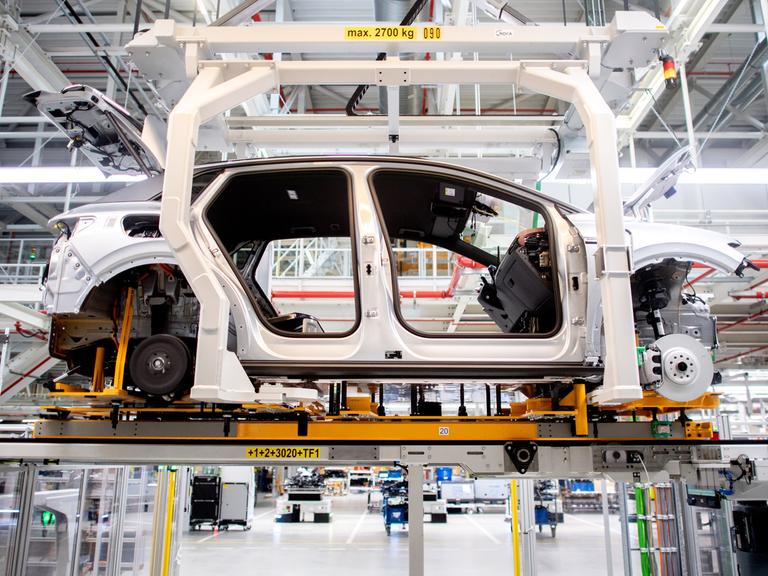 Die Karosserie für ein vollelektrisches Fahrzeug vom Typ Volkswagen ID.4 wird auf einem Transportsystem durch eine Halle im Volkswagen-Werk Emden transportiert. 