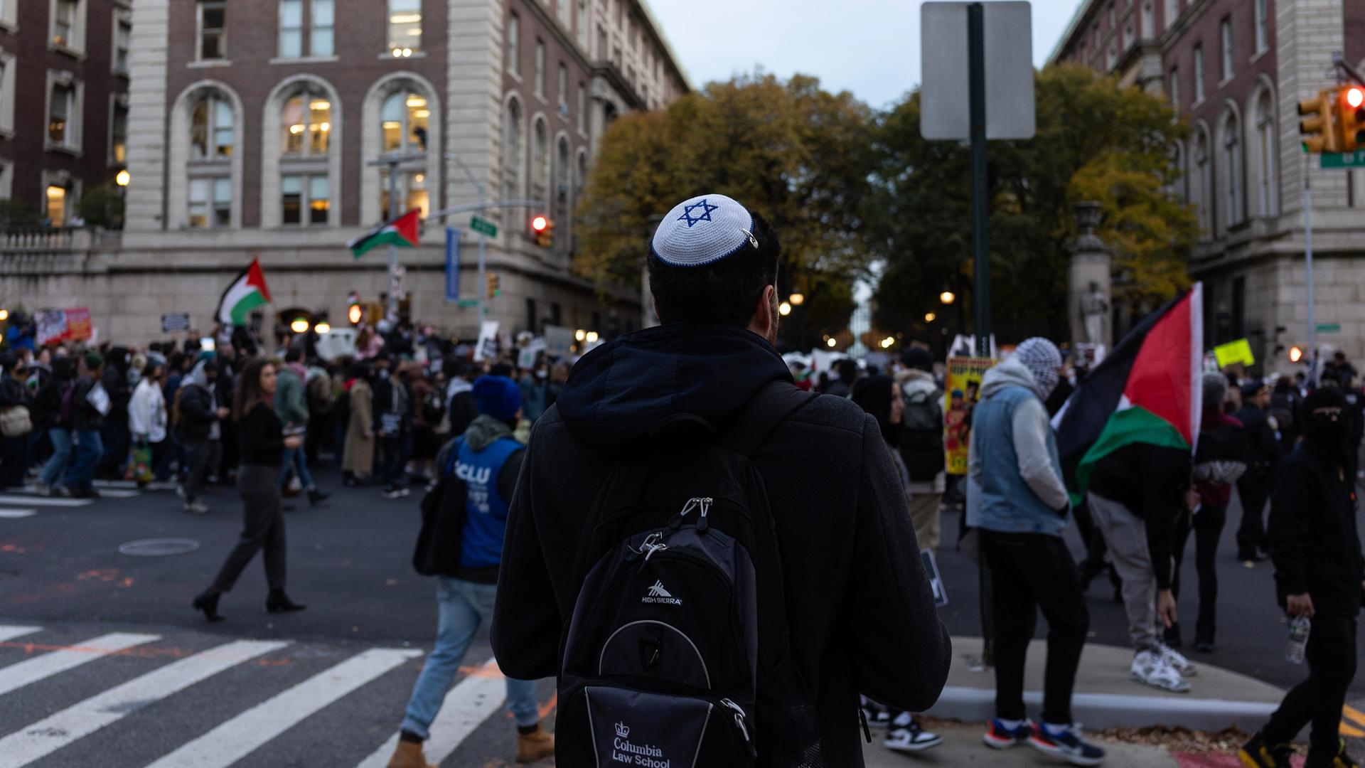 Ein Mann mit Kippa schaut einem propalästinensischen Protest zu.