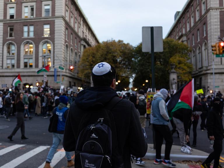 Ein Mann mit Kippa schaut einem propalästinensischen Protest zu.