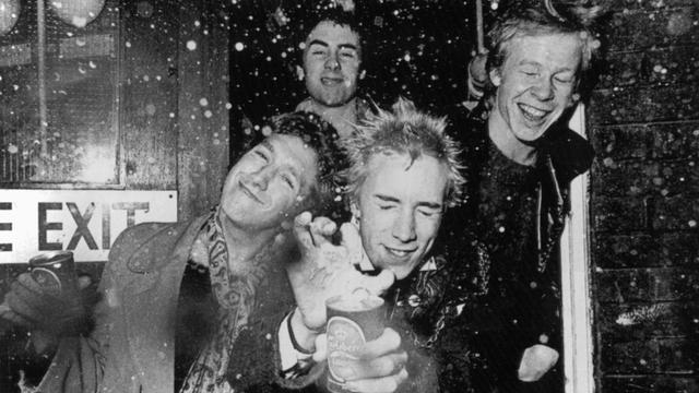 Das schwarz-weiß-Foto zeigt die britische Punk-Rock-Band „Sex Pistols“. Sie lassen am 3. Dezember 1976 in London eine Dose Bier explodieren. Vorne Steve Jones (l) und Bandleader und Sänger Jonny Rotten (M), dahinter Glen Matlock und Paul Cook (r).