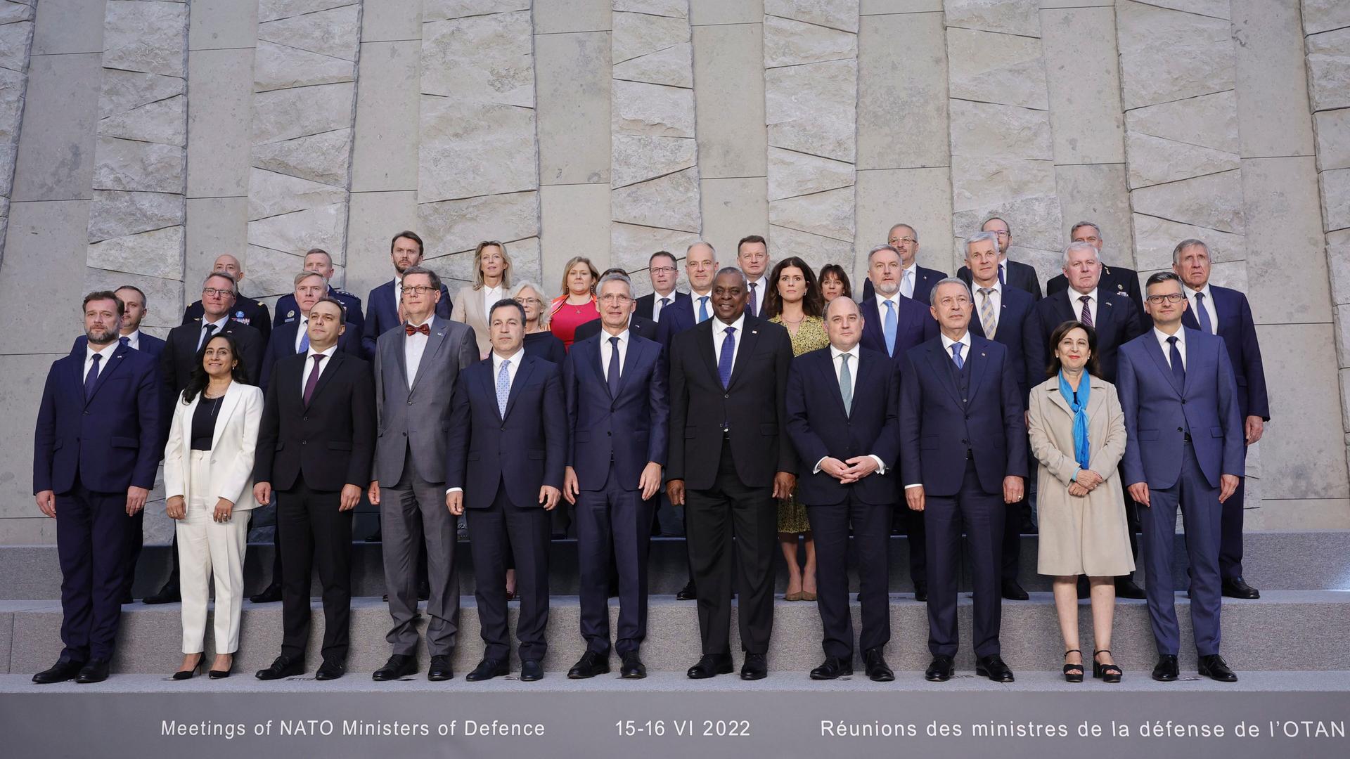 Die Ministerinnen und -minister stehen zu einem Gruppenfoto neben- und hintereinander vor einer grauen Wand.