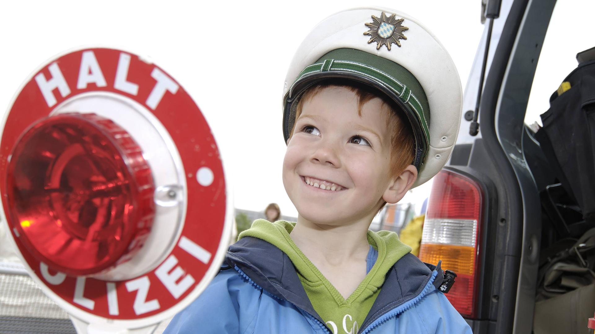 Kleiner Junge spielt mit Polizeimütze und Kelle Polizist