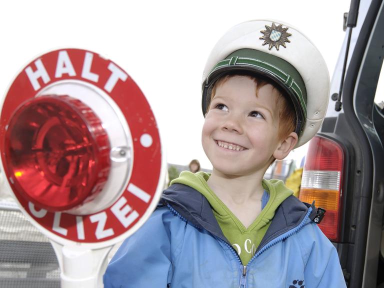 Kleiner Junge spielt mit Polizeimütze und Kelle Polizist