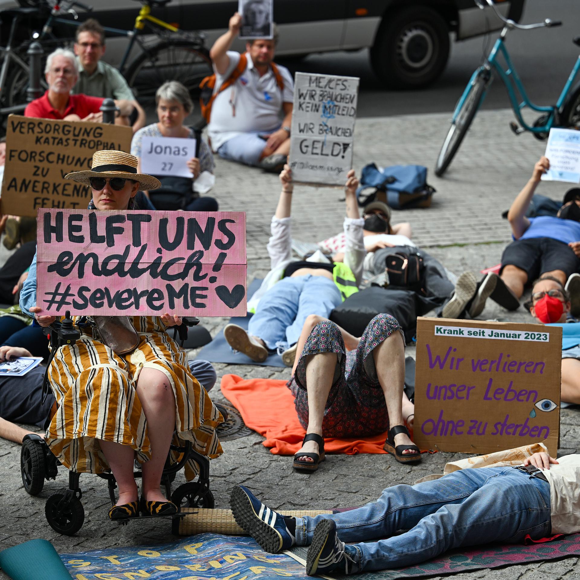Demonstranten liegen vor dem Roten Rathaus und halten Schilder in die Höhe, darauf steht unter anderem „Wir verlieren unser Leben, ohne zu sterben“. 