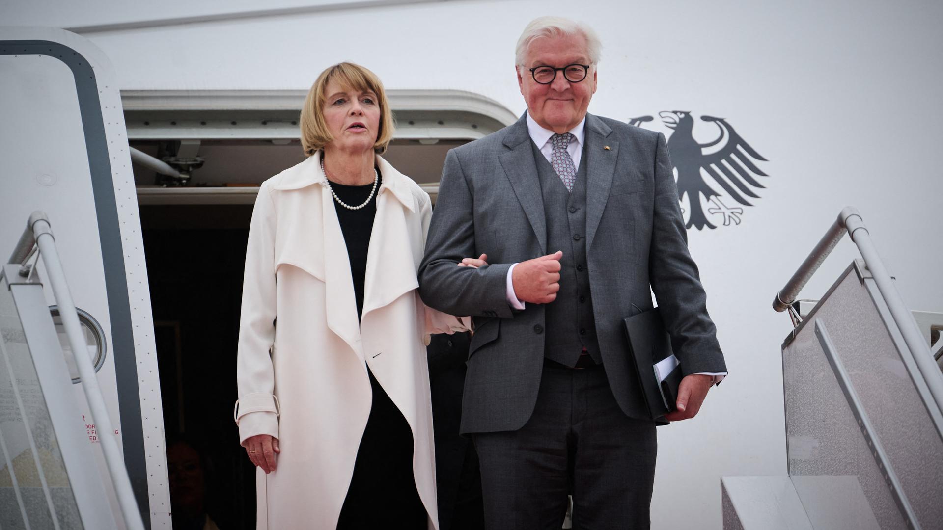 Bundespräsident Frank-Walter Steinmeier und seine Frau Elke Büdenbender kommen auf dem Flughafen Paris Orly an. Die beiden stehen vor der geöffneten Tür des Regierungsflugzeugs und sind in Begriff, die Treppe zum Vorfeld herunterzugehen.