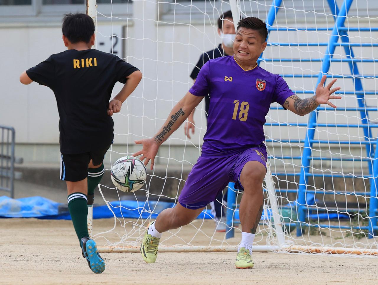 Der ehemalige Fußballnationaltorhüter Myanmars, Pyae Lyan Aung, hält beim Fußballspiel mit Kindern einen Schuss eines Jungen. 