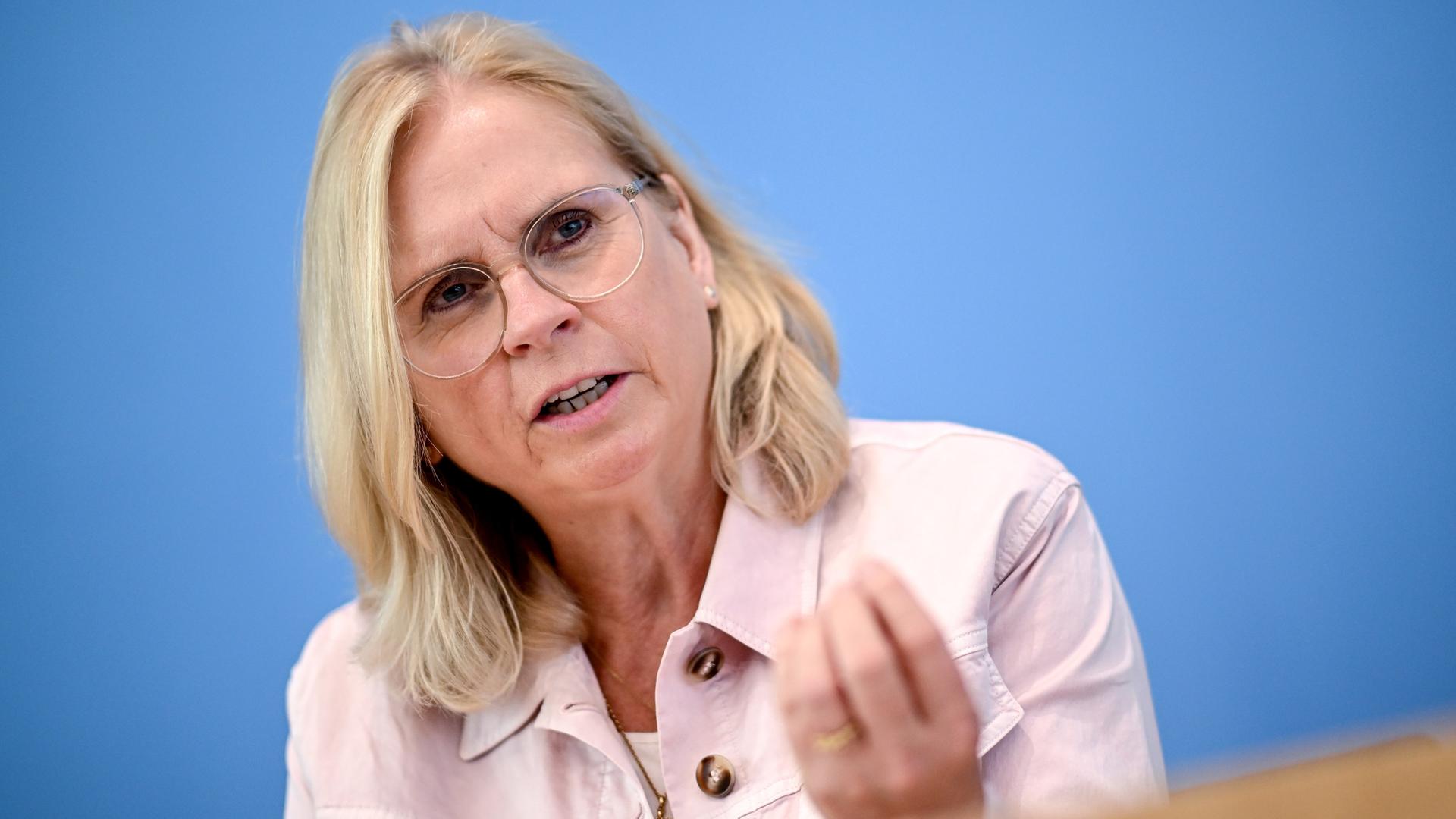 Andrea Lindholz (CSU) sitzt in einem rosa Kostüm in der Pressekonferenz vor blauem Hintergrund.