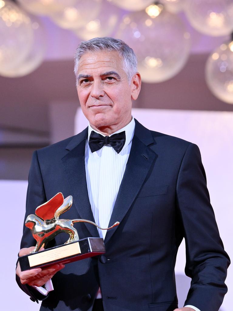 US-Schauspieler George Clooney steht bei den Filmfestspielen in Venedig im eleganten Anzug da. Er hält in einer Hand den Goldenen Löwen, den Ehrenpreis für sein Lebenswerk. US-Schauspieler George Clooney steht bei den Filmfestspielen in Venedig im eleganten Anzug da. Er hält in einer Hand den Goldenen Löwen, den Ehrenpreis für sein Lebenswerk.