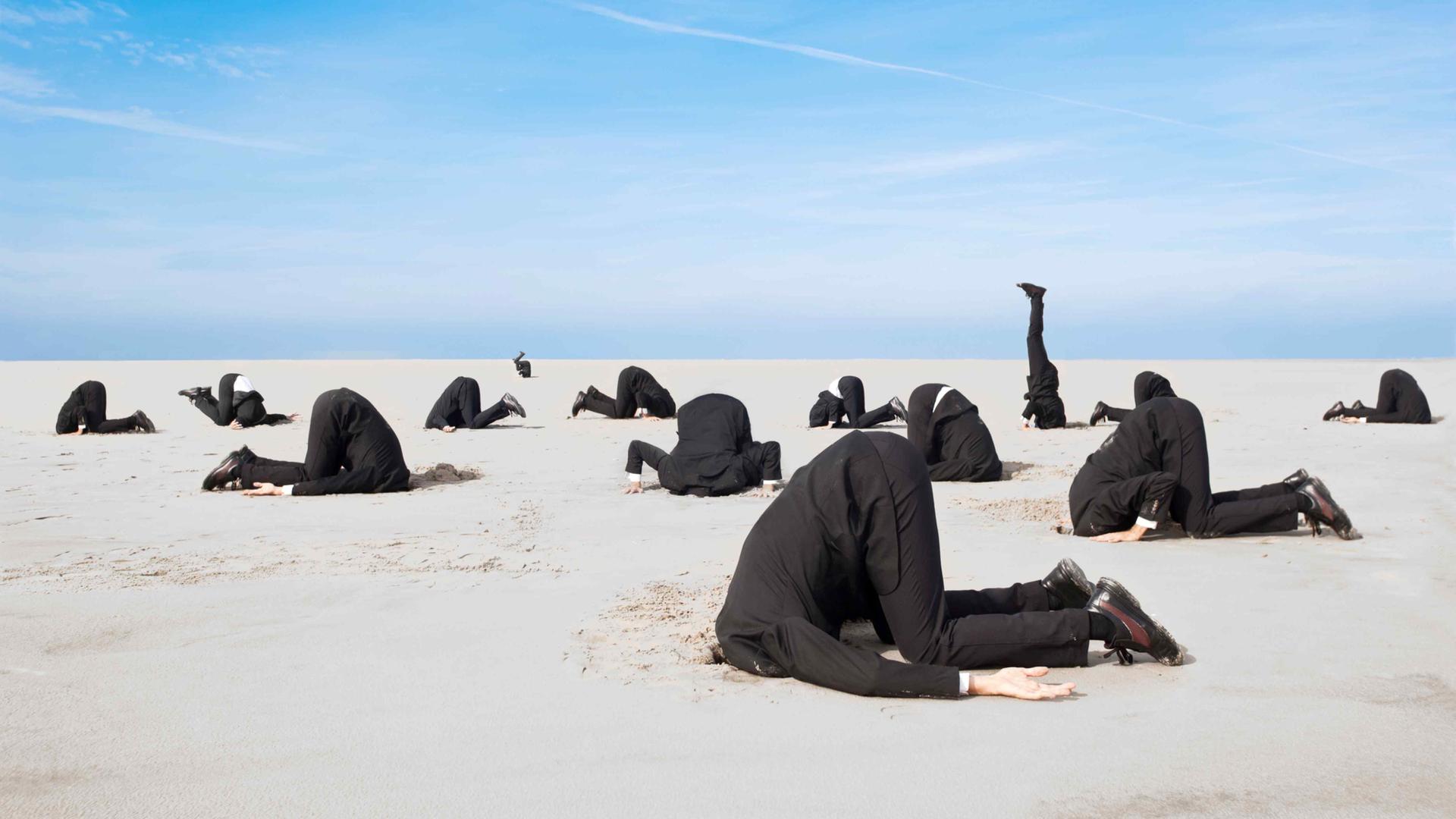 Ein Dutzend Businessmänner in Anzügen stecken vor blauem Himmel die Köpfe in den Sand.