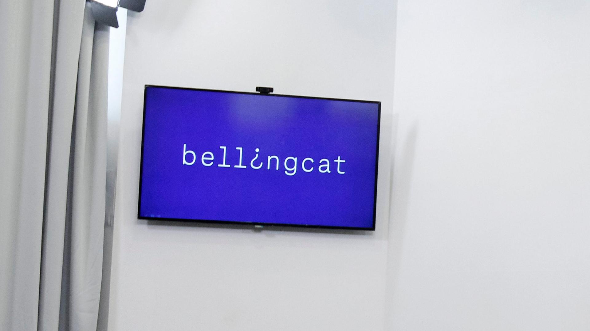 Ein Flatscreen zeigt das Logo des Recherchenetzwerkes Bellingcat.