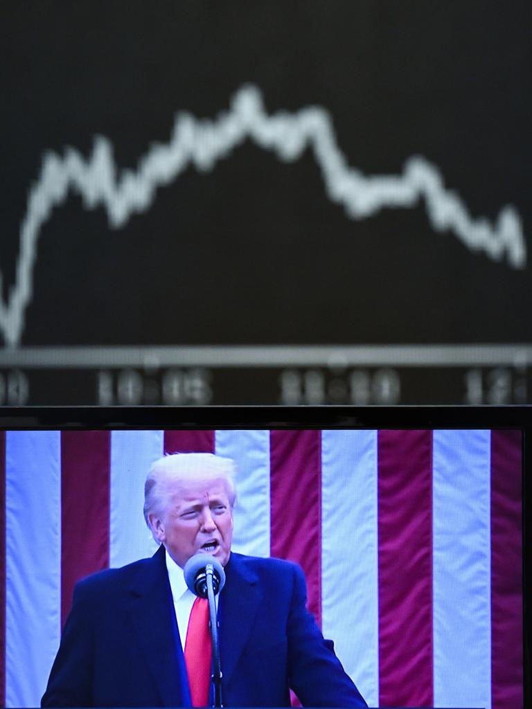 Hinter einem Fernsehmonitor, auf dem US-Präsident Donald Trump zu sehen ist, zeigt die Anzeigetafel mit der Dax-Kurve fallende Kurse. 