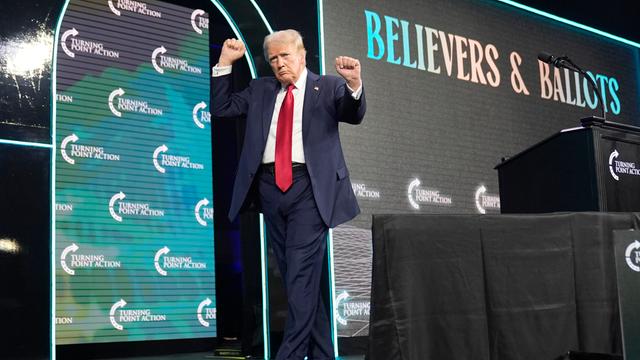 Donald Trump verlässt nach einer Rede eine Bühne mit triumphierender Gestik 